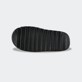 A top-down view of the black sole of a Combat Corner CRNR Foam Slide. The outsole features heavy, horizontal traction ridges running from the toe to the heel for grip, with a smooth, rounded edge at the very back.