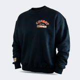 Left front view of the Fire Fight Crew crewneck sweater by Combat Corner, featuring an arched orange and white graphic on the left chest that reads "Combat Fight Shop Corner" and a gold cuff tag.