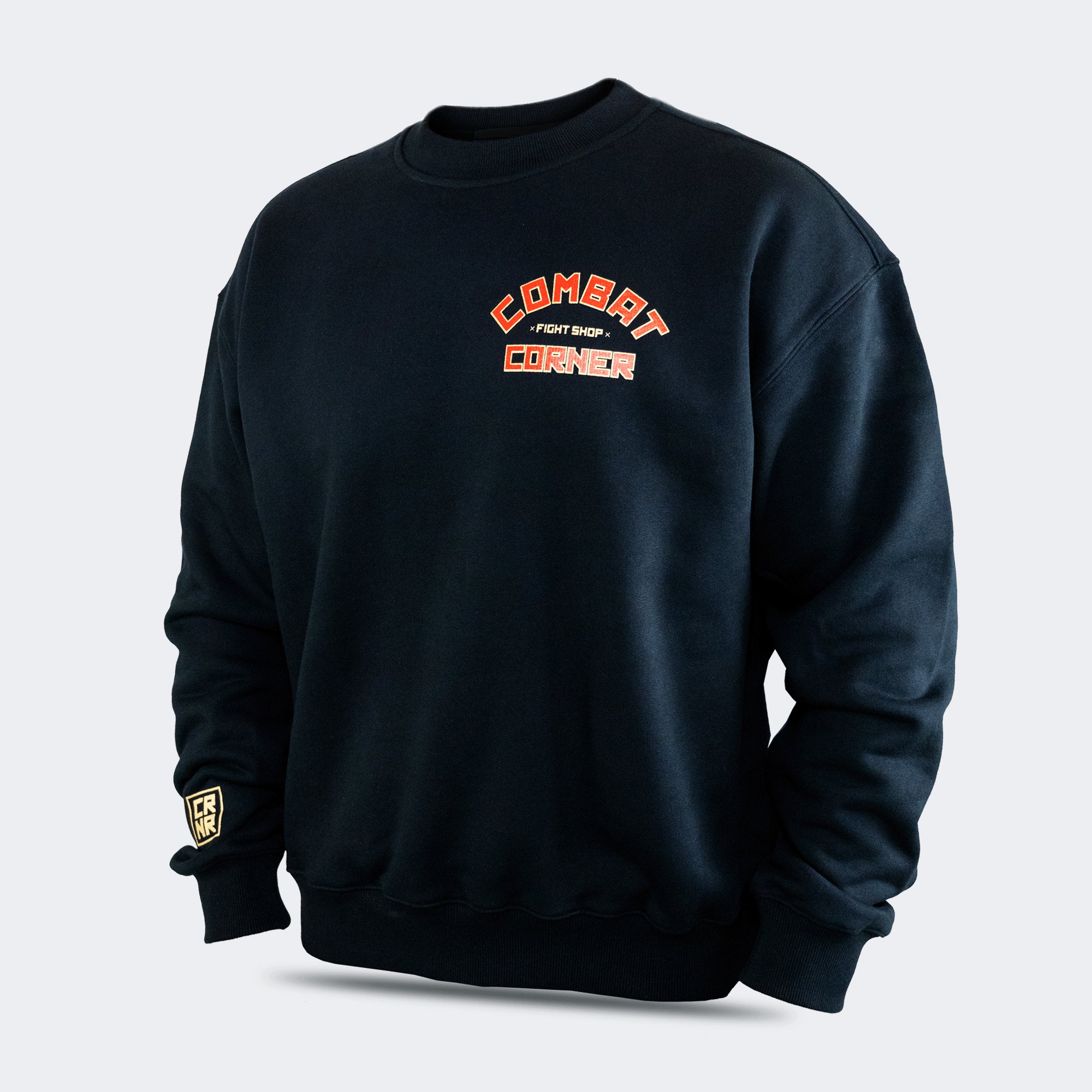 Left front view of the Fire Fight Crew crewneck sweater by Combat Corner, featuring an arched orange and white graphic on the left chest that reads "Combat Fight Shop Corner" and a gold cuff tag.