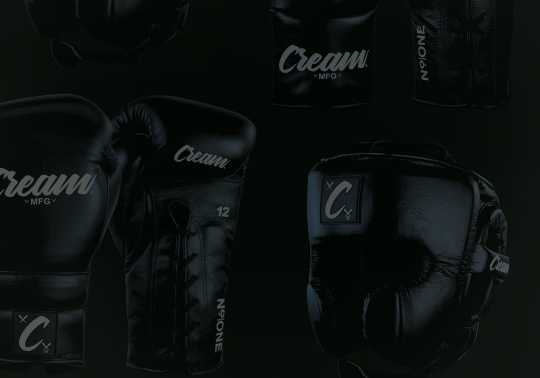 A product display of black combat sports gear from Combat Corner against a dark background, including Mexican style boxing gloves and headgear. 