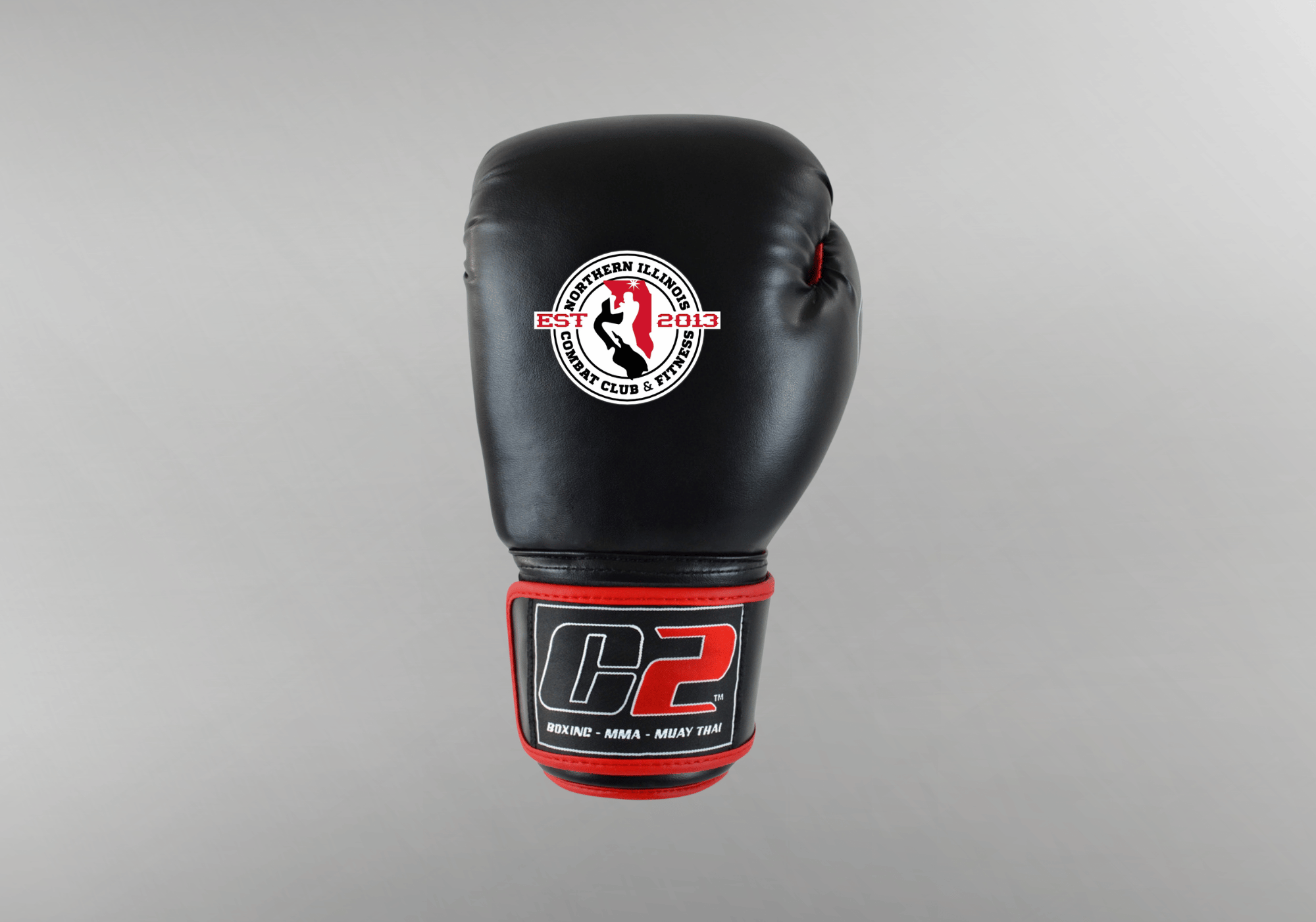 A co-branded custom black leather boxing glove by Combat Corner, featuring a circular Northern Illinois Combat Club & Fitness logo on the knuckle area and a C2 brand patch on the red-trimmed wrist strap.