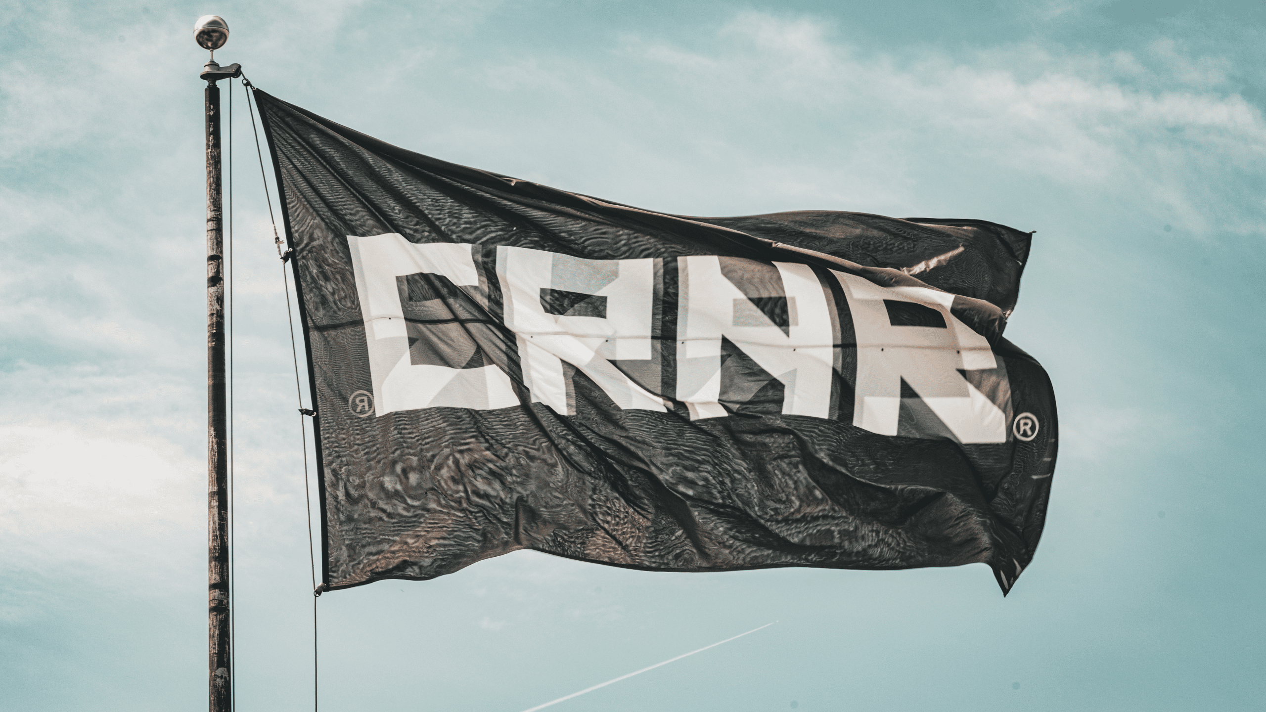 A close up photo of the CRNR flag at full mast flying in front of the CRNR Store at the Combat Corner Headquarters in Milwaukee, Wisconsin.