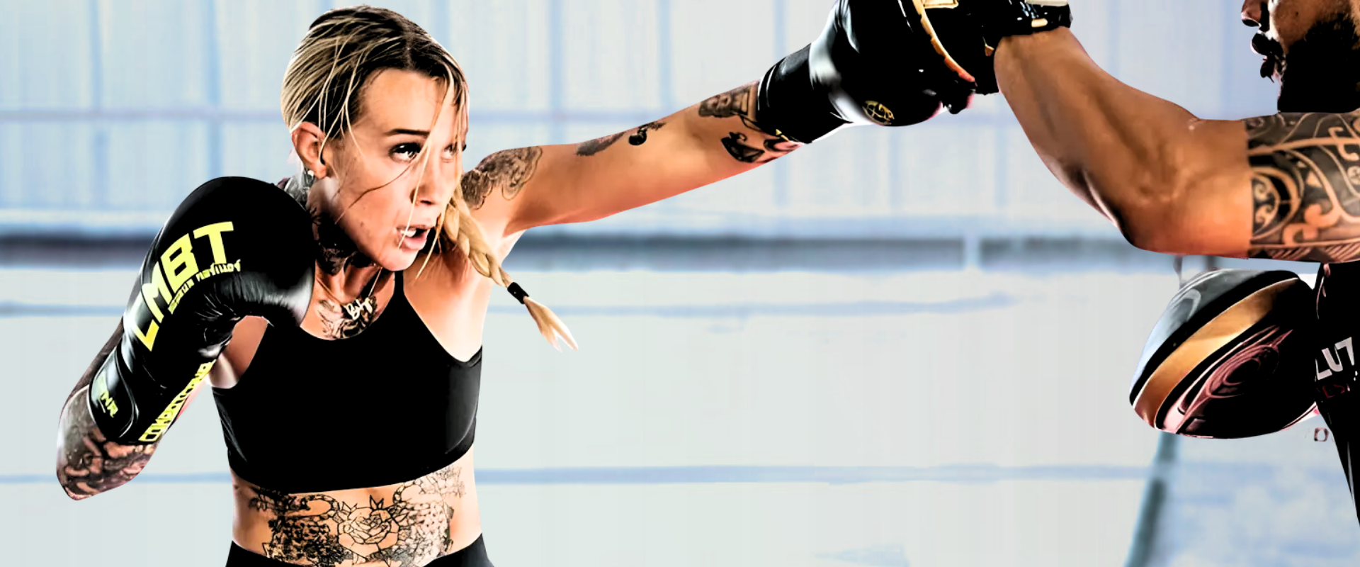 Dynamic action shot of a focused, tattooed pro female fighter Taylor Starling throwing a straight punch into a coach's mitt while wearing Combat Corner’s TrainAir Boxing Gloves.