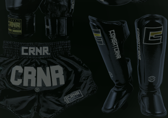 A product display of black combat sports gear from Combat Corner against a dark background, including Muay Thai shorts, Muay Thai boxing gloves, and punch mitts. 