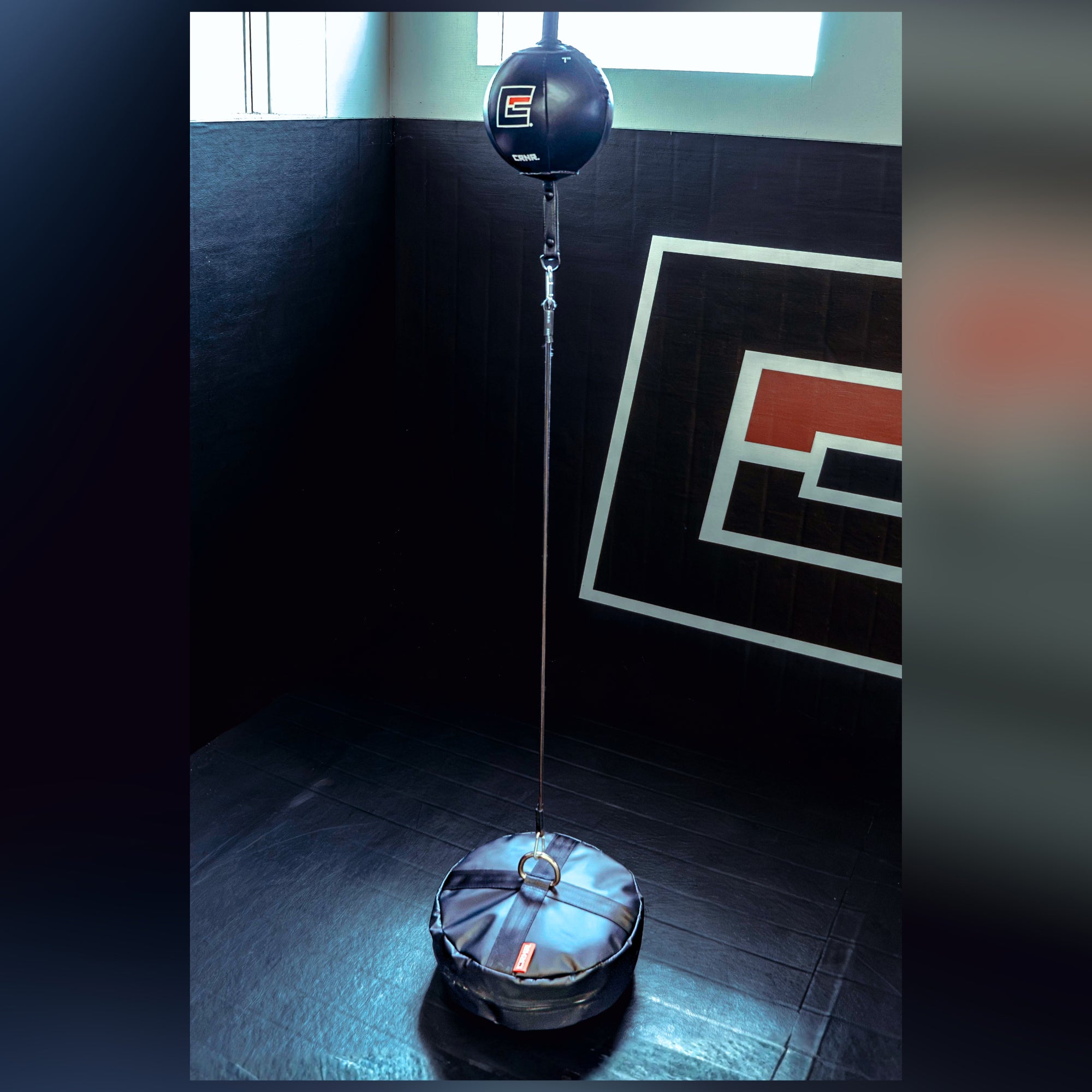 An in use example photo of the black CRNR Punching Bag Anchor with a top metal ring attached to a double end punching bag. 
