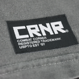 Product photo of Combat Corner’s exclusive Pinnin’ & Winnin’ Relaxed Tee. This photo shows a detail, close up on the delux embroidered CRNR logo tag on the side of Combat Corner’s Pinnin’ & Winnin’ Faded Navy Relaxed Tee. This CRNR tee offers the same softness and comfort as your favorite, well-loved vintage tee.