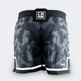 Rear view of Combat Corner CRNR ISO black fight shorts. Displays a centered, square black interlocking "CRNR" logo patch on the gathered elastic waistband. A thin white horizontal stripe runs just above the black bottom hem on both legs, and a small white logo print sits on the lower right leg.