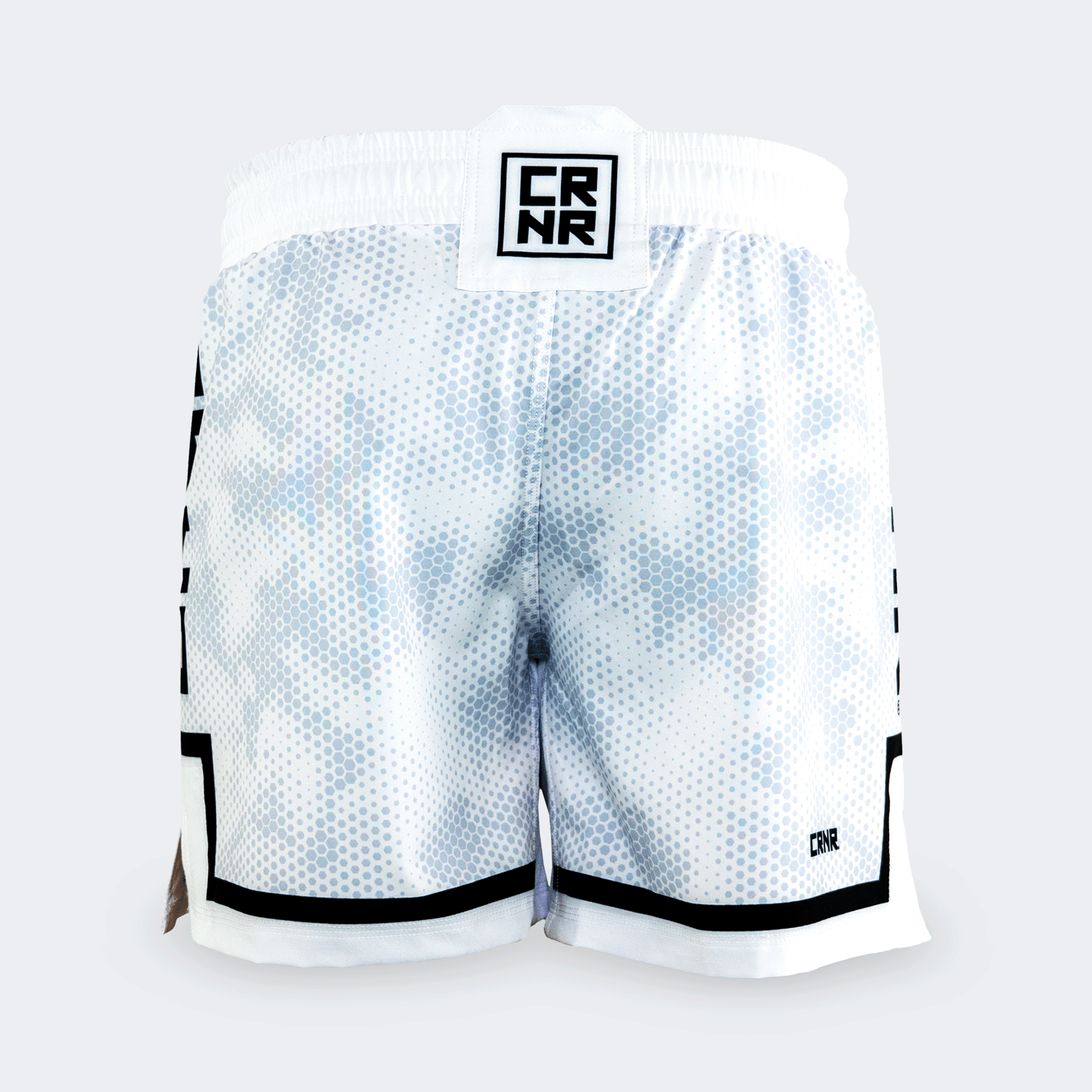 Rear view of the white Combat Corner hybrid fight shorts against a light grey background. The back displays the continuous hexagonal digital camo pattern, a square black and white "CRNR" logo patch on the center of the waistband, and a small black "CRNR" logo printed near the lower right hem.