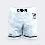 White Combat Corner hybrid fight shorts shown from the front against a light grey background. The shorts feature a white and grey hexagonal digital camouflage pattern, a wide white elastic waistband with a black "CRNR" logo patch centered, a black and red stylized "E" logo on the left thigh, and black trim along the bottom hems.