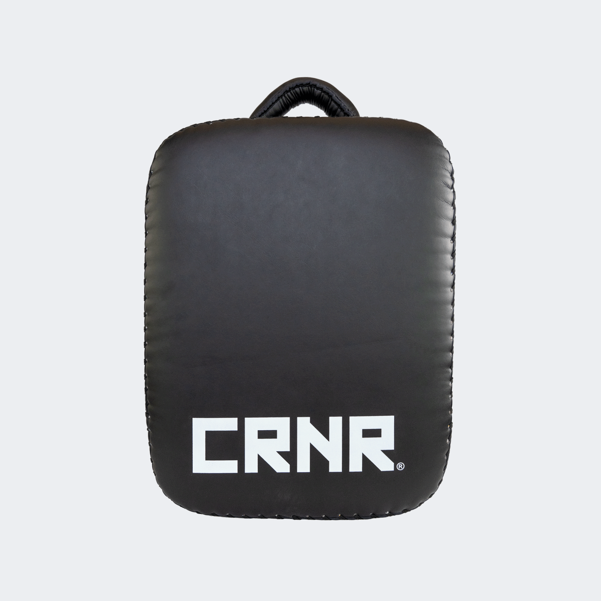 Back view of the HMITV Low Kick Pad Lite, a large, black leather martial arts low kick shield pad by Combat Corner against a light grey background, featuring a white block "CRNR" logo on the striking surface.