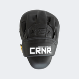 The back of the black HMITV Curved Punch Mitts by Combat Corner against a solid light grey background, showcasing the curved hand compartment and front striking surface.