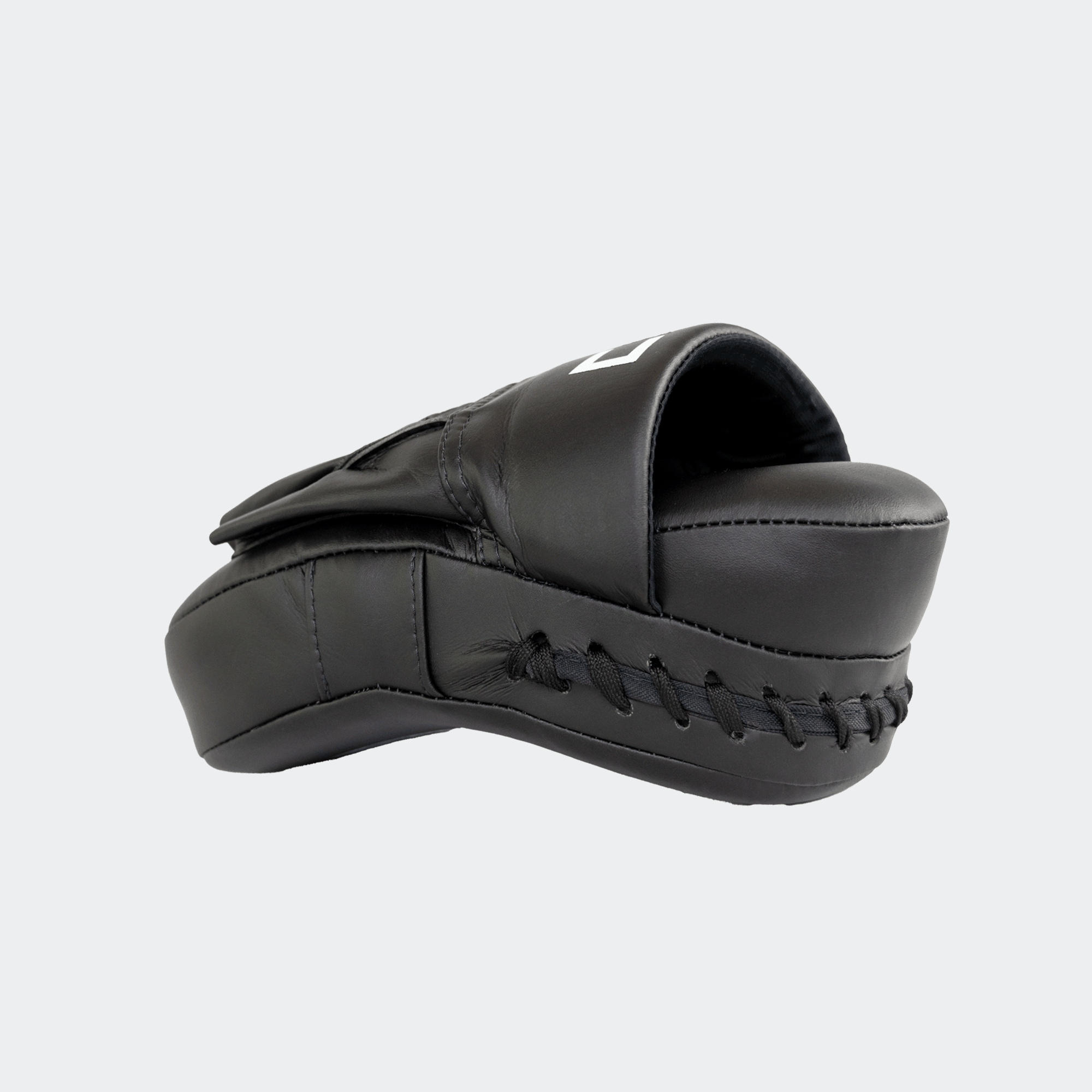 The left side view of the black HMITV Curved Punch Mitts by Combat Corner against a solid light grey background, showcasing the curved hand compartment and front striking surface.
