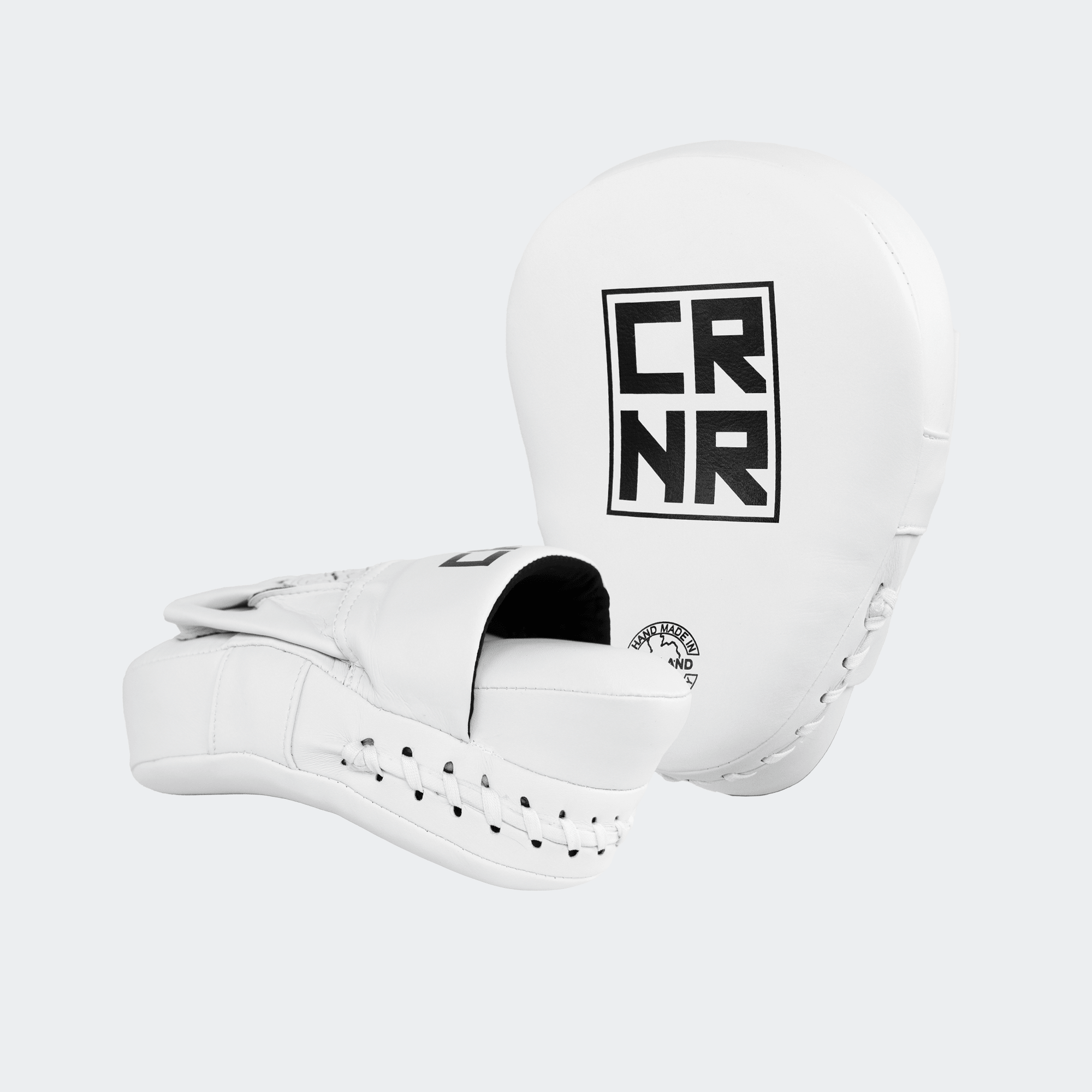 A pair of professional white HMITV Curved Punch Mitts by Combat Corner against a solid light grey background, showcasing the curved hand compartment and front striking surface.