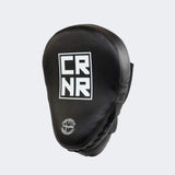 The front of the black HMITV Curved Punch Mitts by Combat Corner against a solid light grey background, showcasing the curved hand compartment and front striking surface.