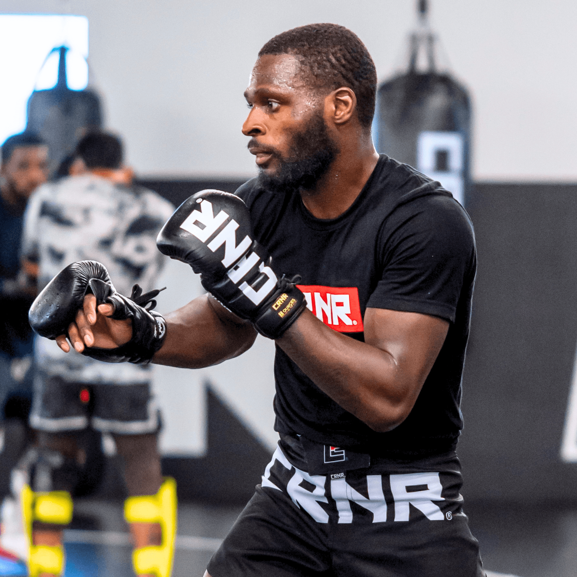 A photo of a left angle view of a pro fighter training with black Combat Corner HMIT Lace Up MMA Sparring Gloves during a sparring session. 