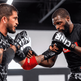 A photo of a profile view of two pro fighters  both training with black Combat Corner HMIT Lace Up MMA Sparring Gloves and exchanging jabs during a sparring session. 
