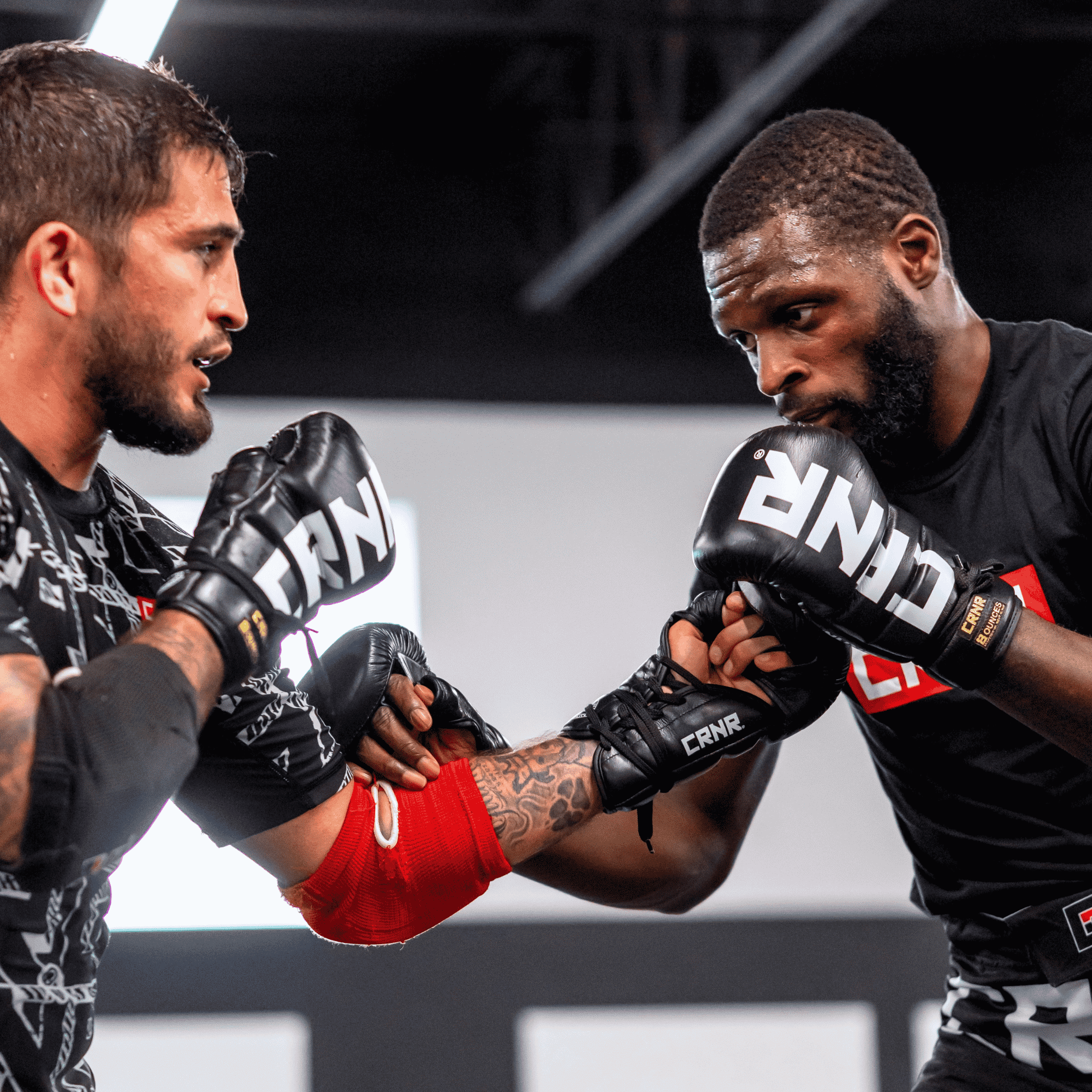 A photo of a profile view of two pro fighters  both training with black Combat Corner HMIT Lace Up MMA Sparring Gloves and exchanging jabs during a sparring session. 
