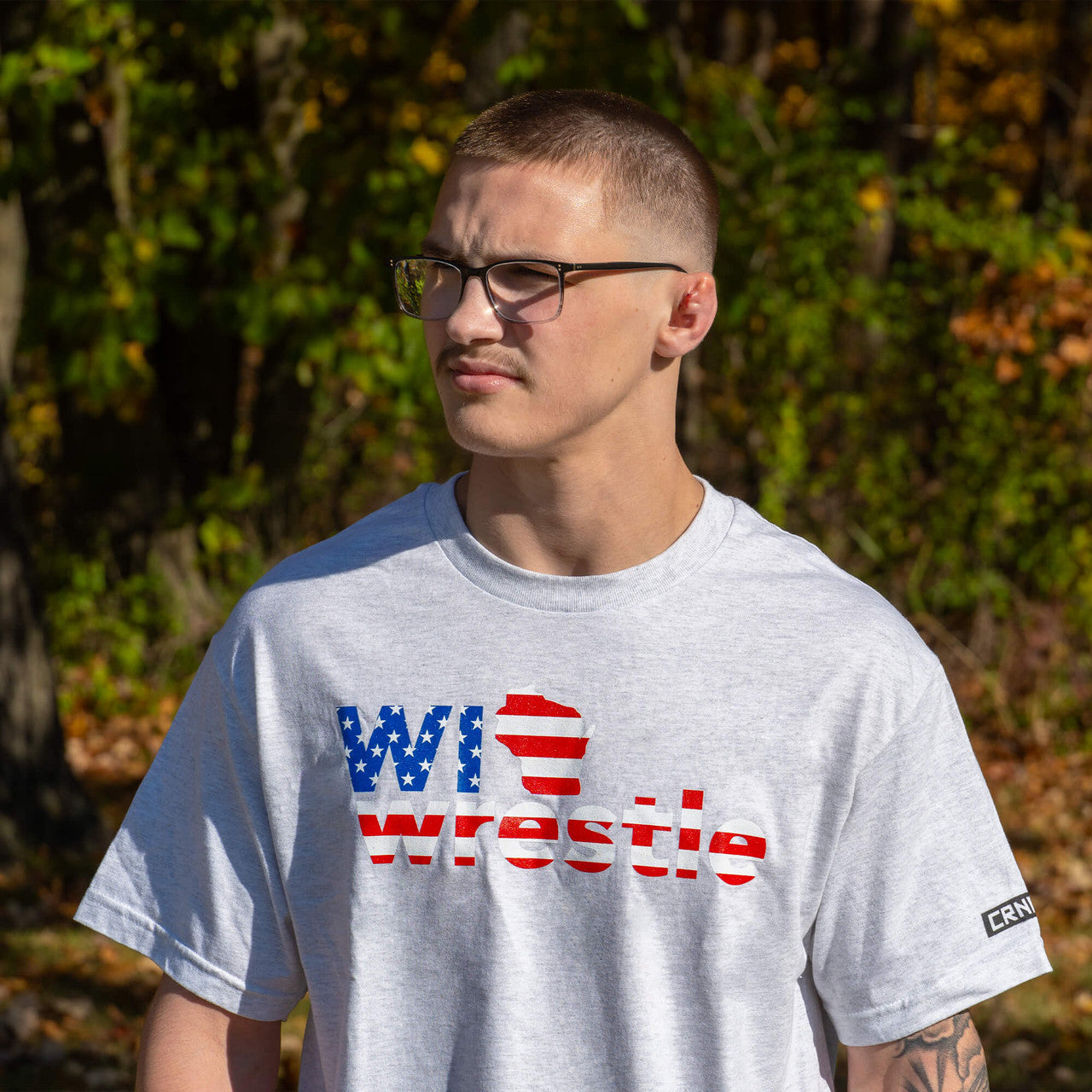 Product photo of Combat Corner’s exclusive WI Wrestle All American Tee. This photo shows the front of Combat Corner’s WI Wrestle All American Tee. This collab All American Tee is part of Combat Corner’s sponsorship of WI Wrestle, the number one news source and fan center for Wisconsin wrestling.