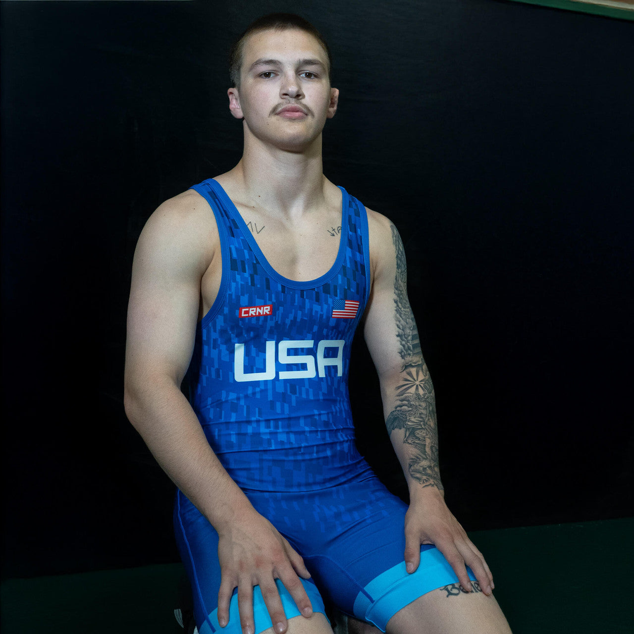 Man kneeling in blue wrestling singlet