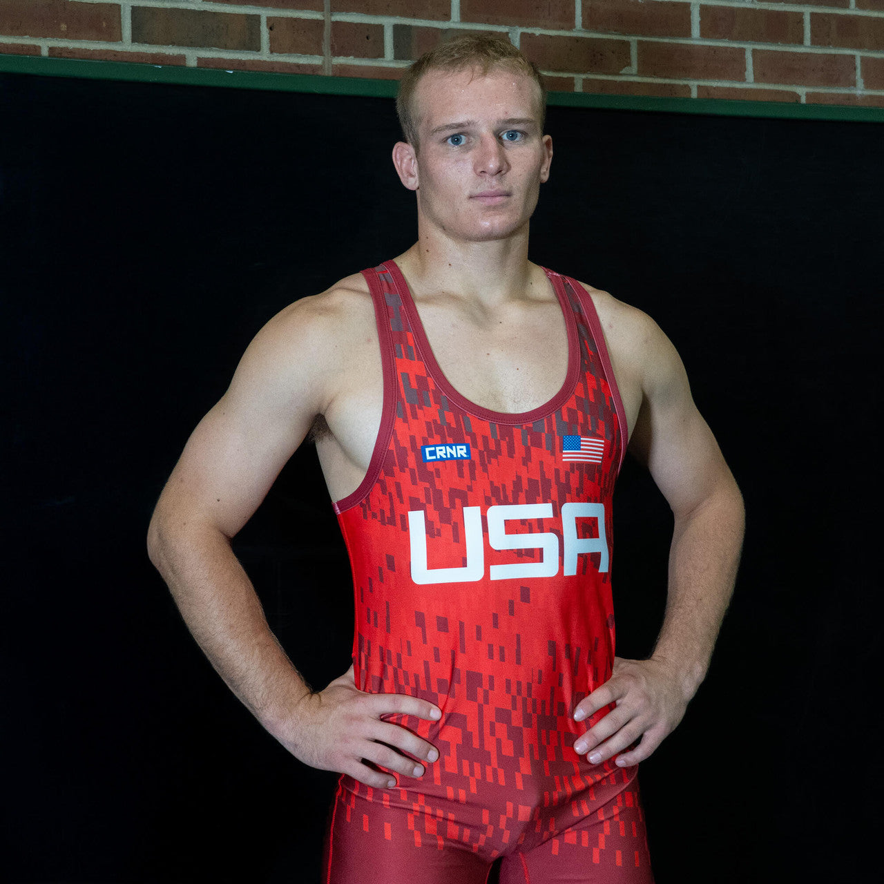 Wrestler standing with arms at his sides in red singlet