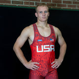 Wrestler standing with arms at his sides in red singlet