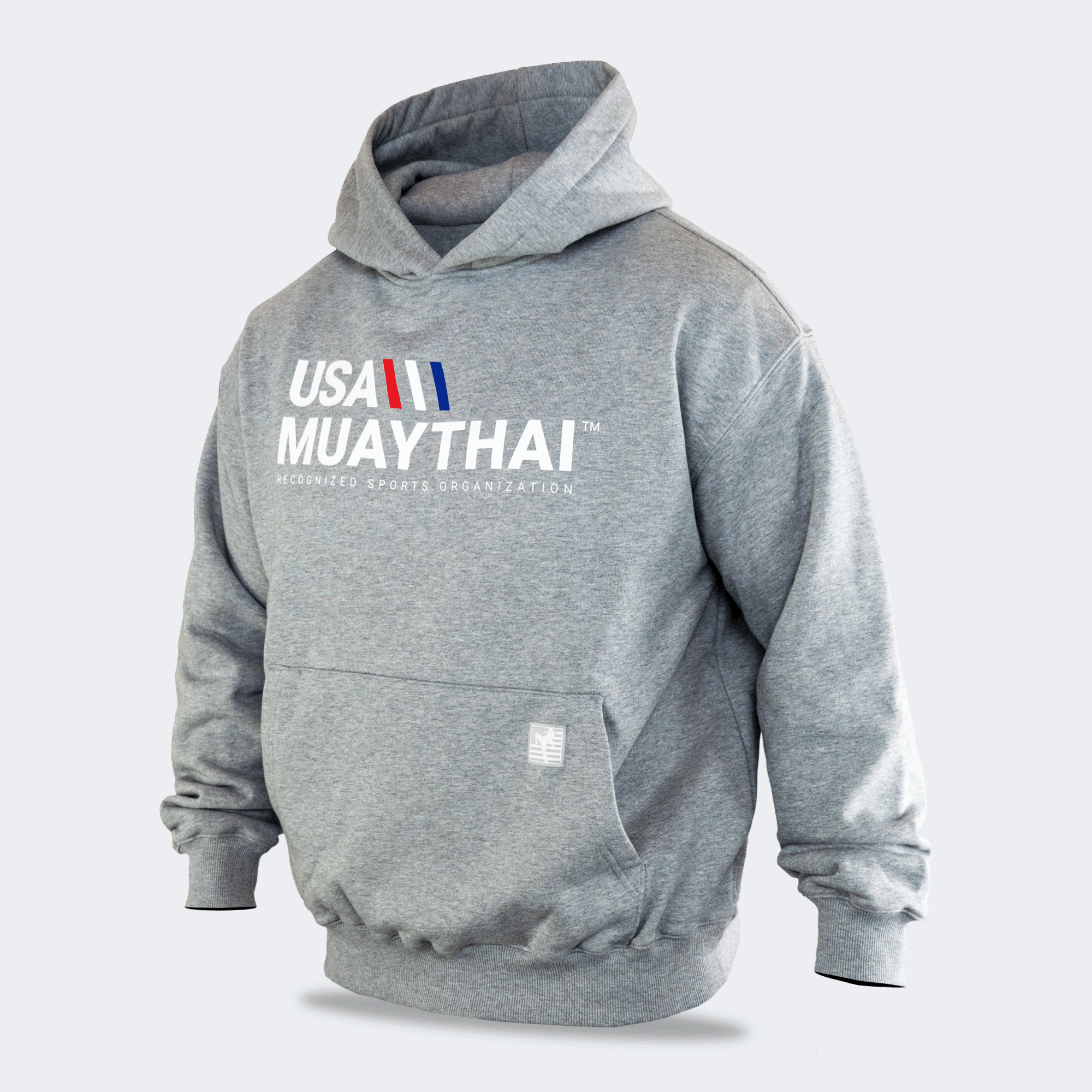 Three-quarters angled view of the gray Combat Corner USA Muay Thai lifestyle hoodie, displaying its heavy-weight fabric construction, relaxed fit, ribbed cuffs, and front graphics.