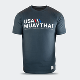 Front studio view of a dark slate blue Combat Corner USA Muay Thai lifestyle t-shirt, showcasing the bold white "USA MUAYTHAI" chest graphic with red and blue accents, along with a small woven flag tag at the lower left hem.